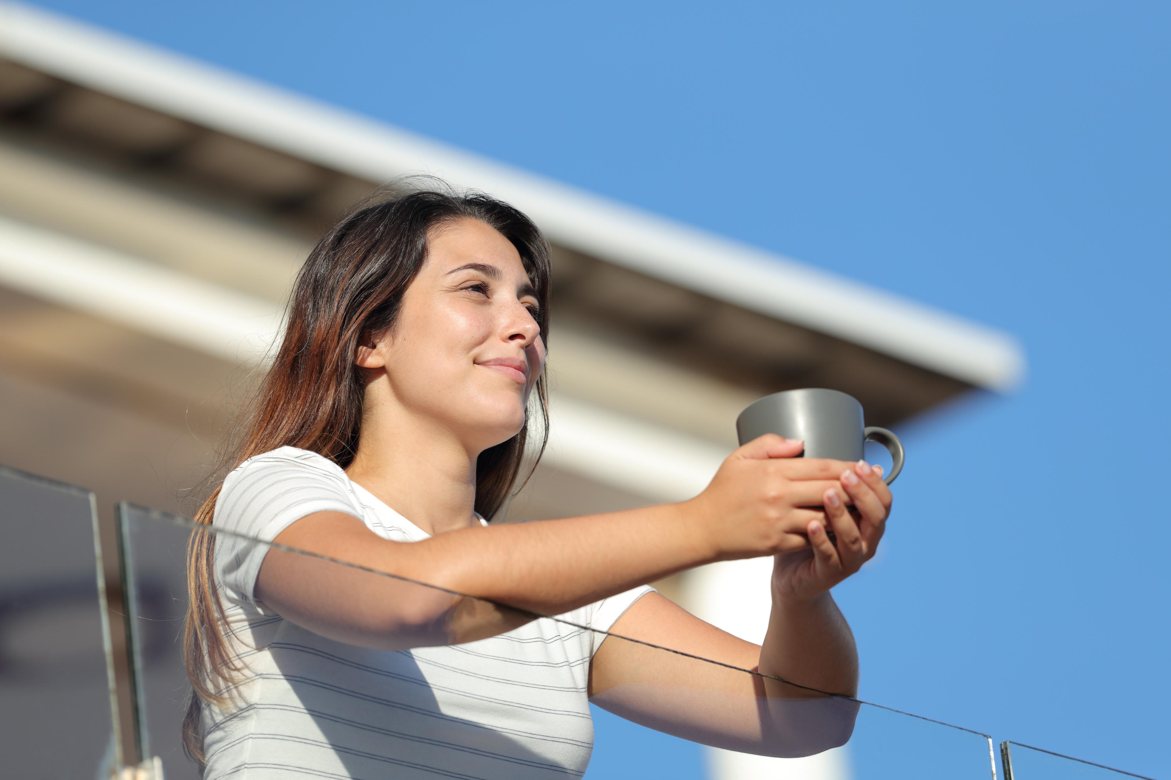 Guest using her phone beside a laptop on a hotel balcony
